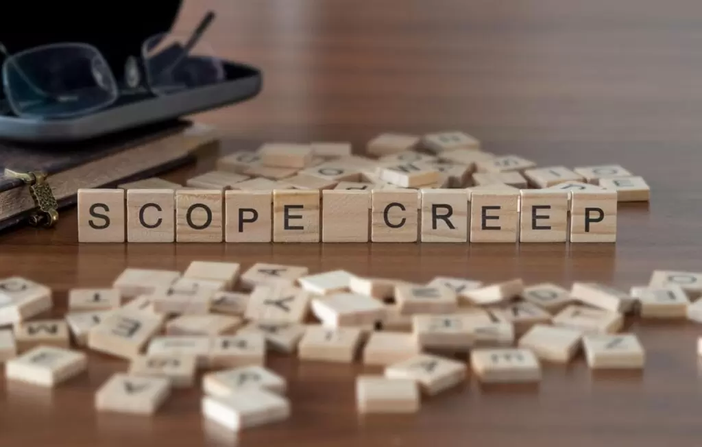 Wooden Scrabble-style tiles spelling “Scope Creep” on a table, symbolizing uncontrolled feature growth in game development projects.