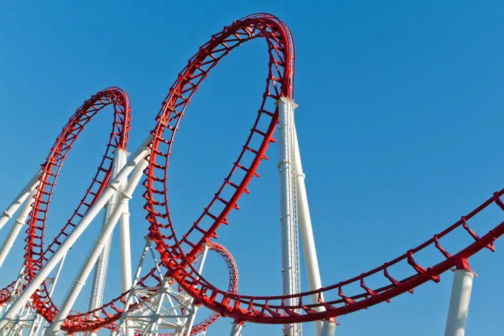 Red roller coaster loops against a clear blue sky, symbolizing the continuous cycles of a gameloop in game development.