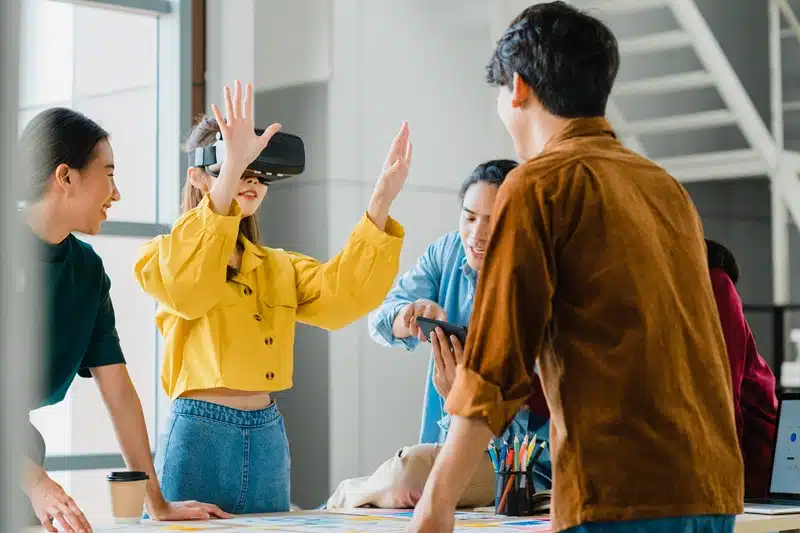 Game development team testing a VR prototype together, with one member wearing a headset and others giving feedback around a table.