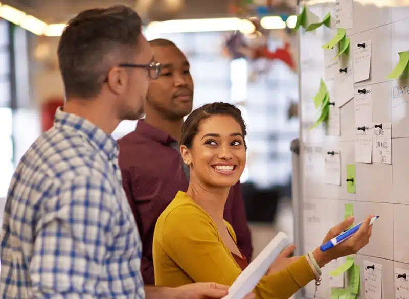 Game development team collaborating during a Scrum sprint planning session with sticky notes on a task board.