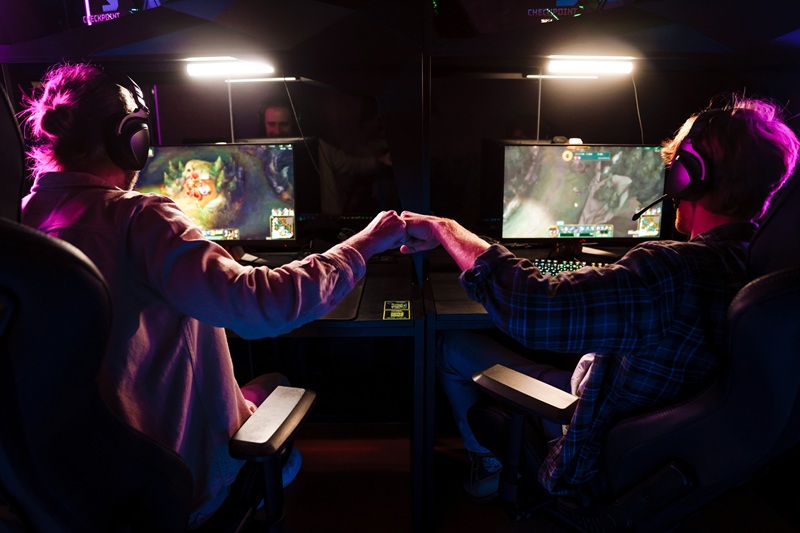 Two game developers fist bumping at their PCs while testing a game, symbolizing teamwork and collaboration in AAA game production.